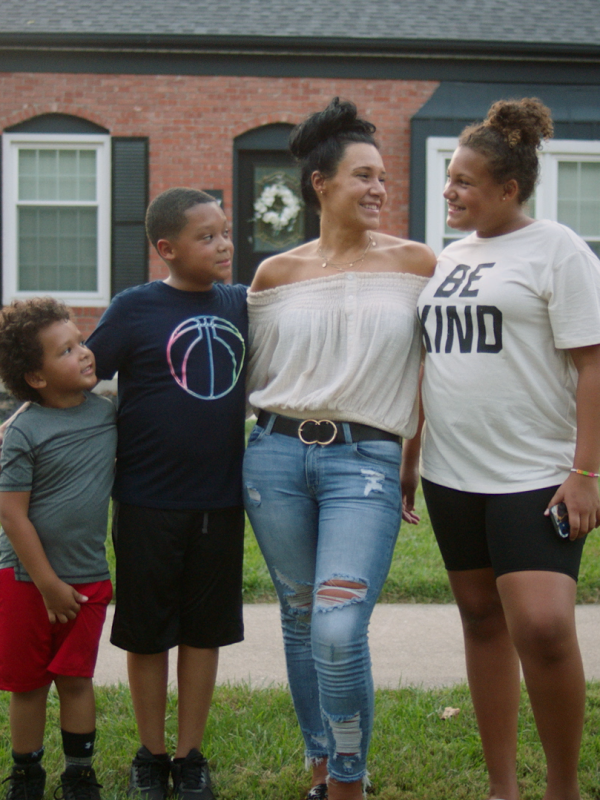 Jessica poses with her family in front of their house