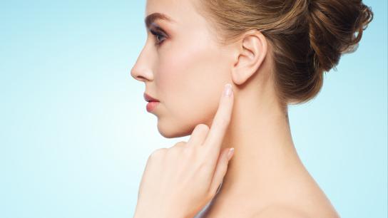 Woman pointing to her earlobe after dermal filler