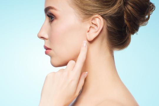 Woman pointing to her earlobe after dermal filler
